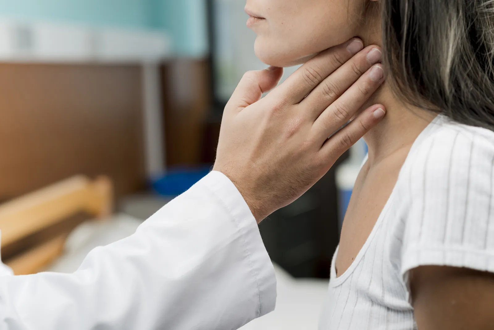 Centre de la thyroïde : un médecin palpe le cou d’une patiente pour examiner la thyroïde.