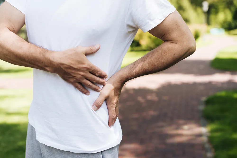 Côte fêlée : un homme se tient le côté, la main appuyée sur ses côtes douloureuses.