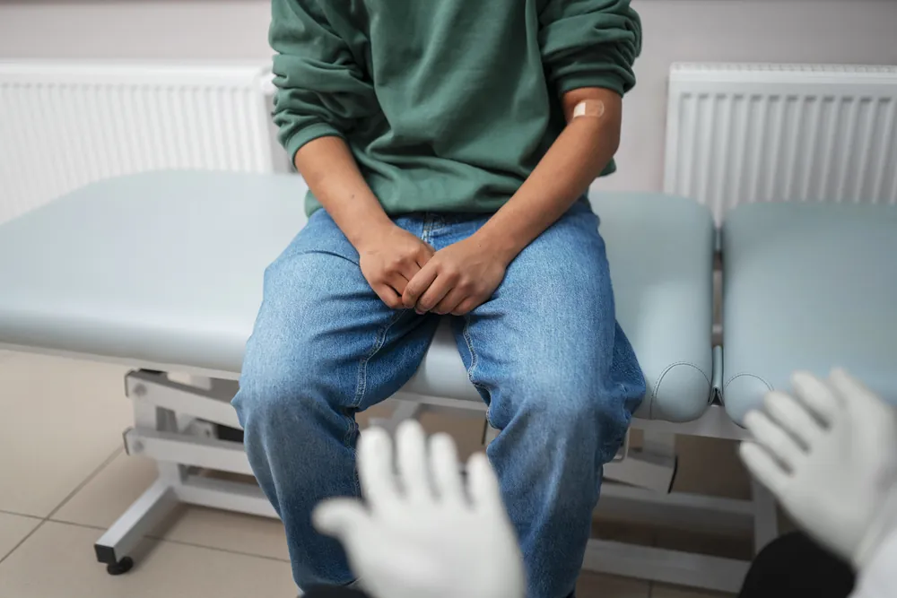 Traitement de l’HBP : un patient assis sur une table d’examen pendant une consultation.