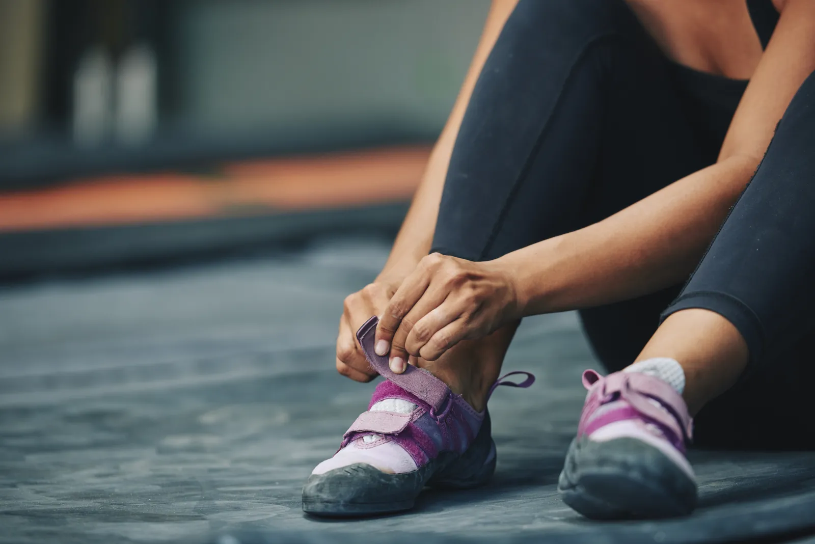 Syndrome de Morton : une sportive assise au sol ajuste des chaussons d’escalade serrés à l’avant du pied.