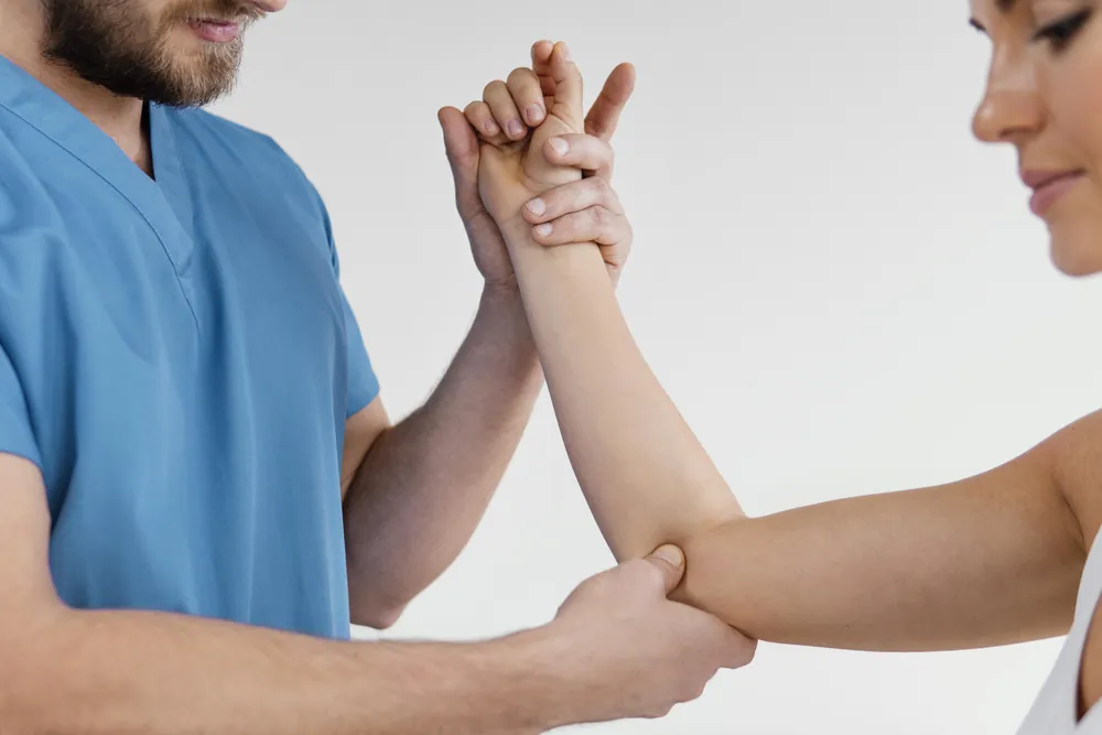 Tennis elbow : un soignant teste le coude d’une patiente en maintenant son poignet et en appuyant sur la face du coude.